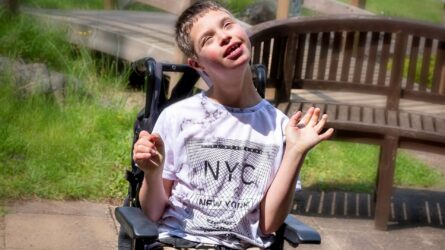 Boy sat in garden waving