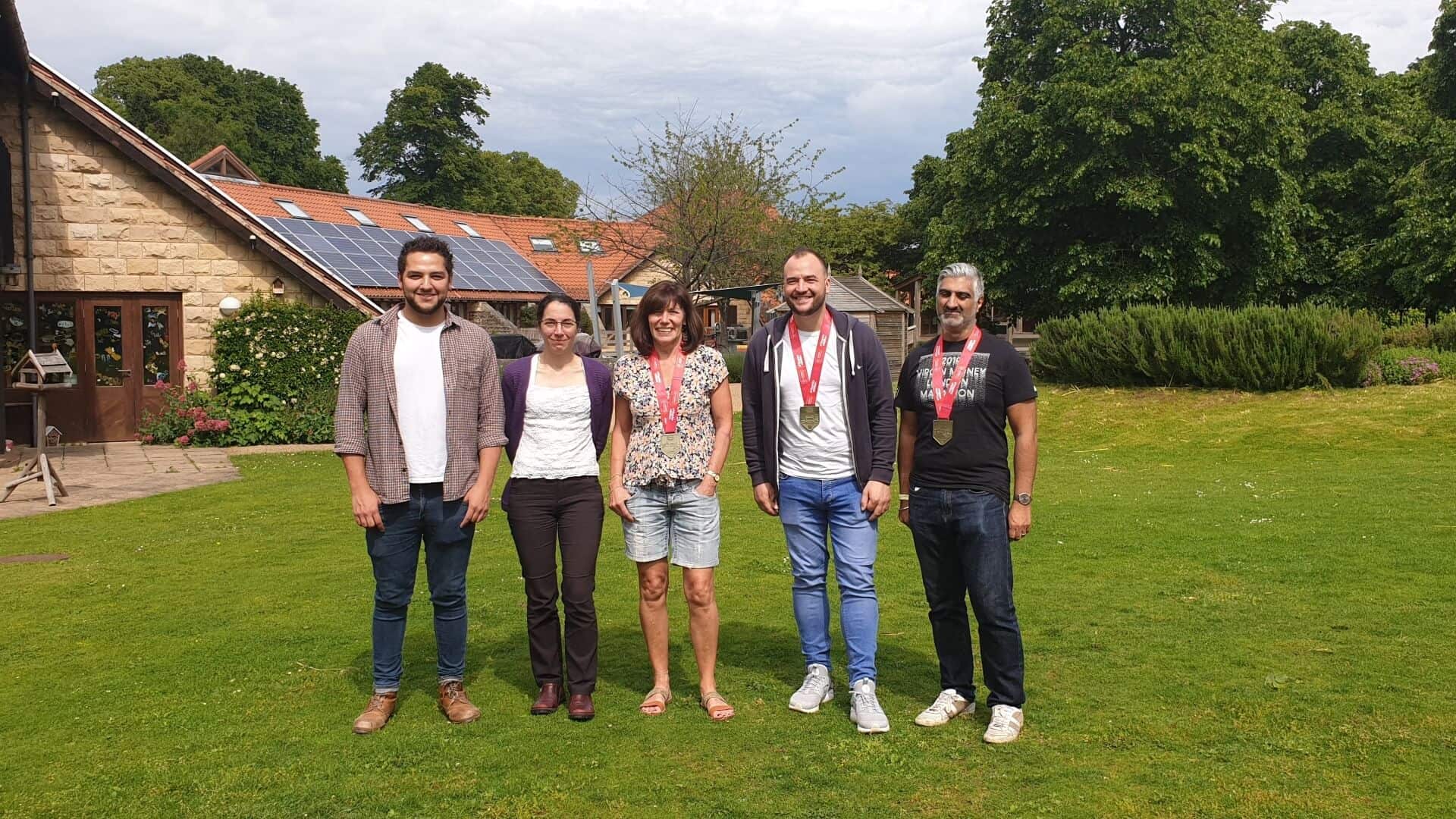 Group of London marathon participants stood in garden of Martin House Children's Hospice