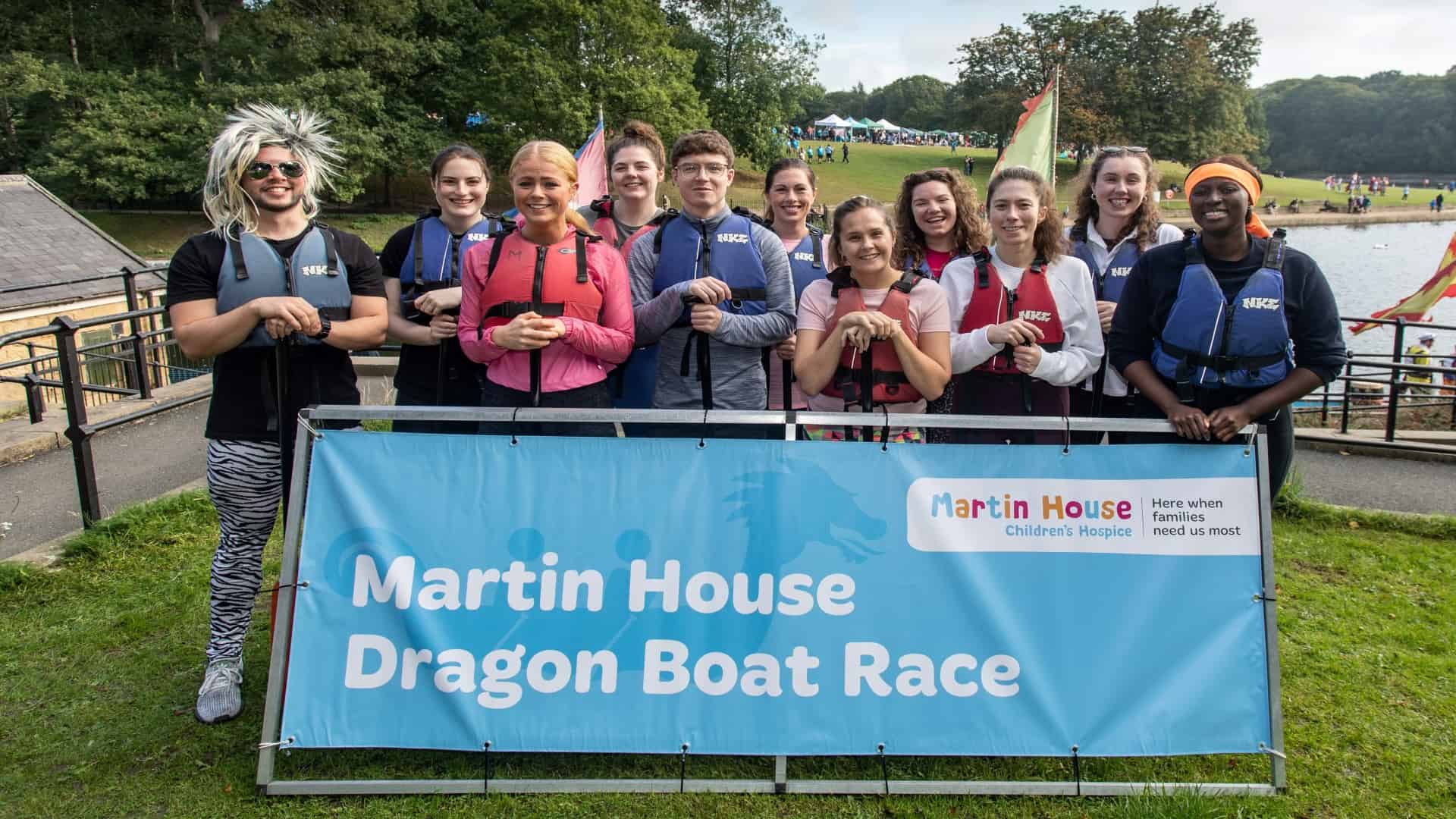 Group of people in fancy dressed holding sign saying Martin House Dragon Boat Race