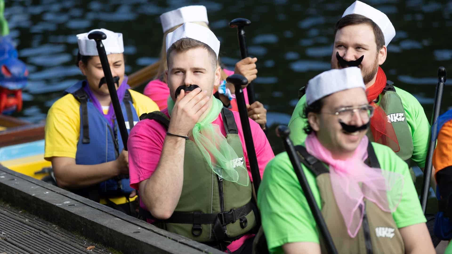 Group of people in fancy dress in a boat on a lake.