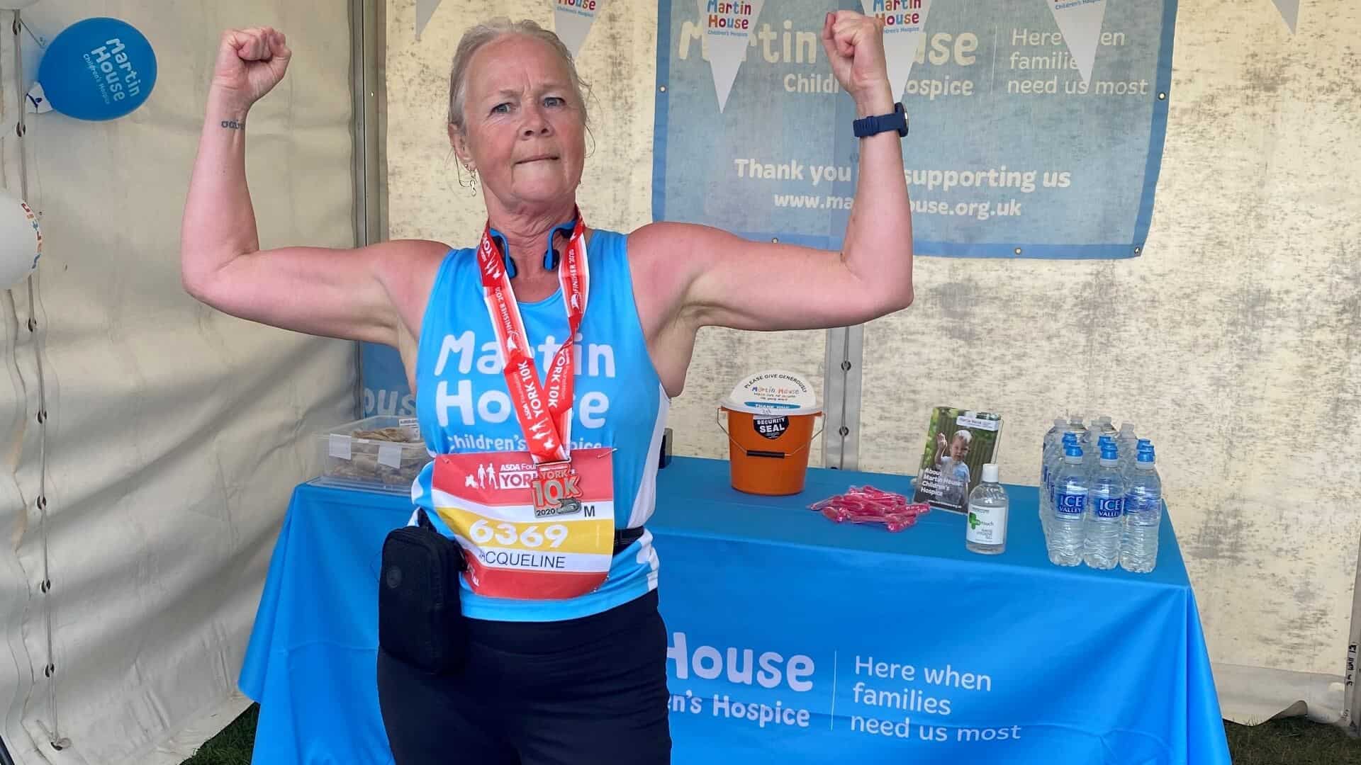 Woman flexing her arms wearing running gear and medal.