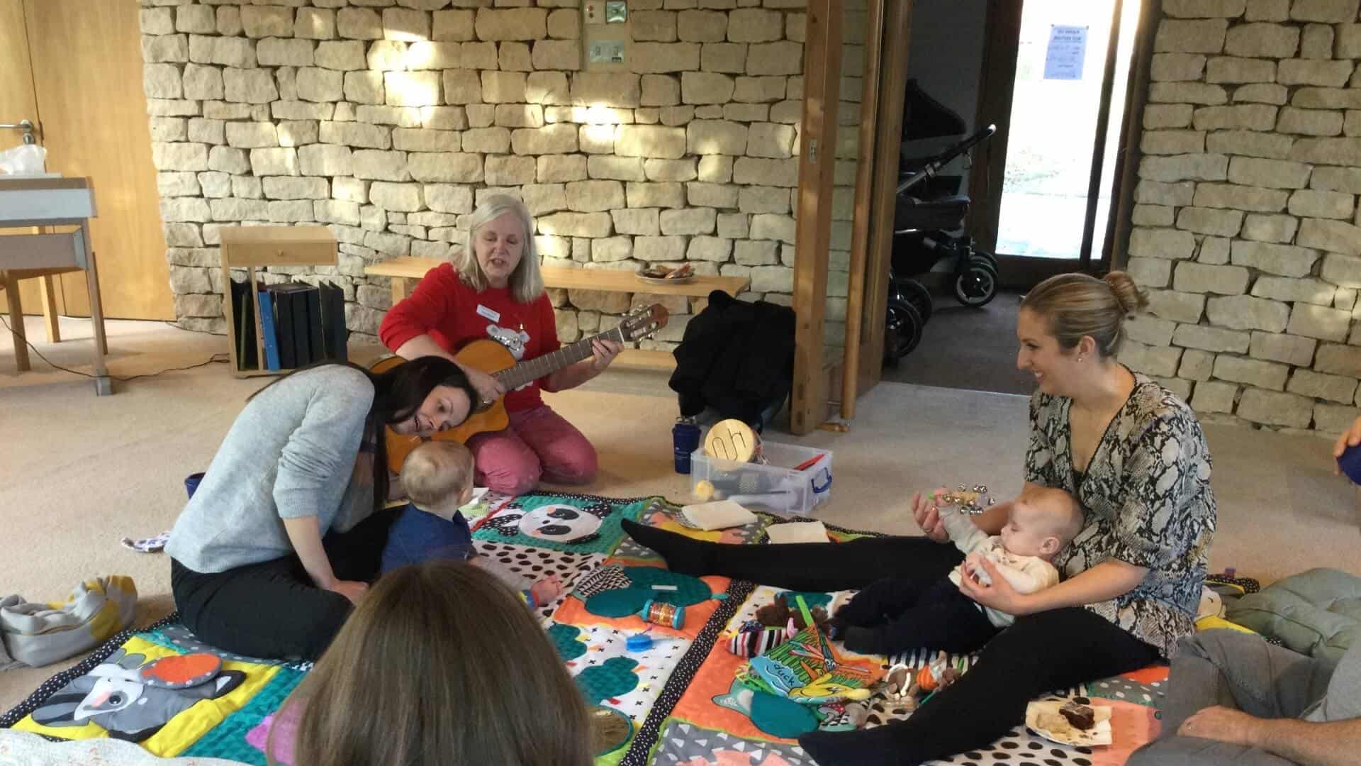 Group of mums and babies with music therapist.