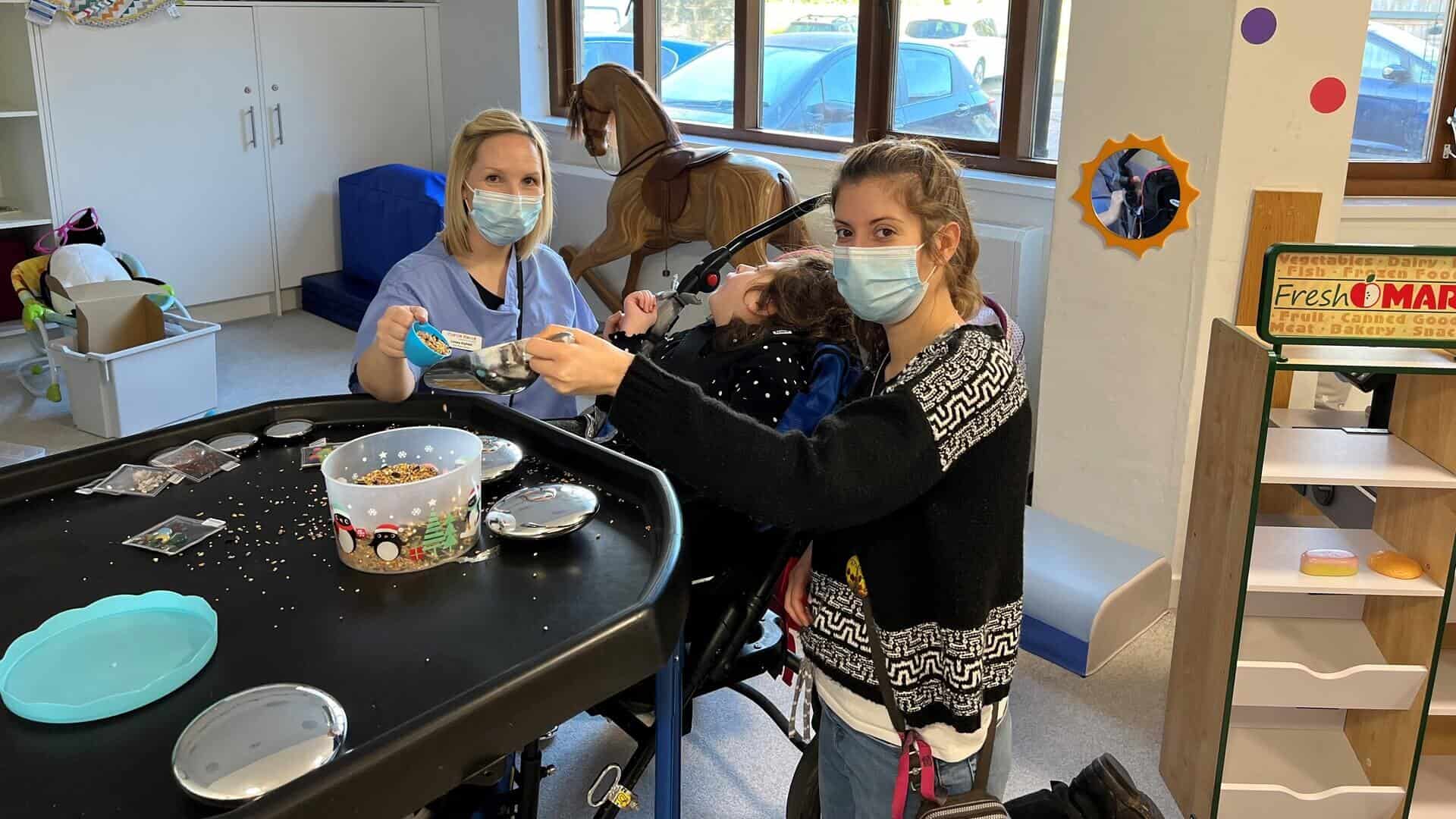 Two women doing arts and crafts with a young child