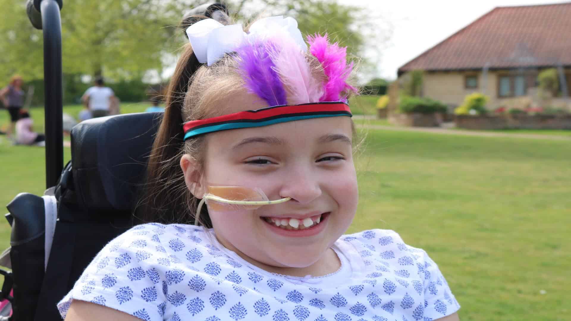 Girl smiling wearing headband with feathers.