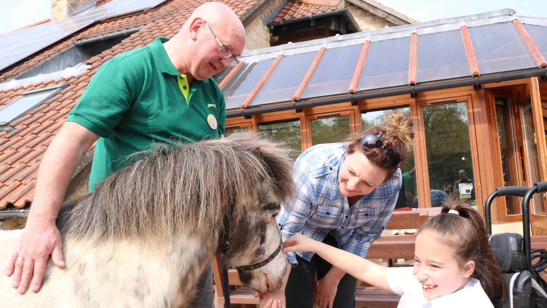 Young girl stroking a pony with a man and woman.