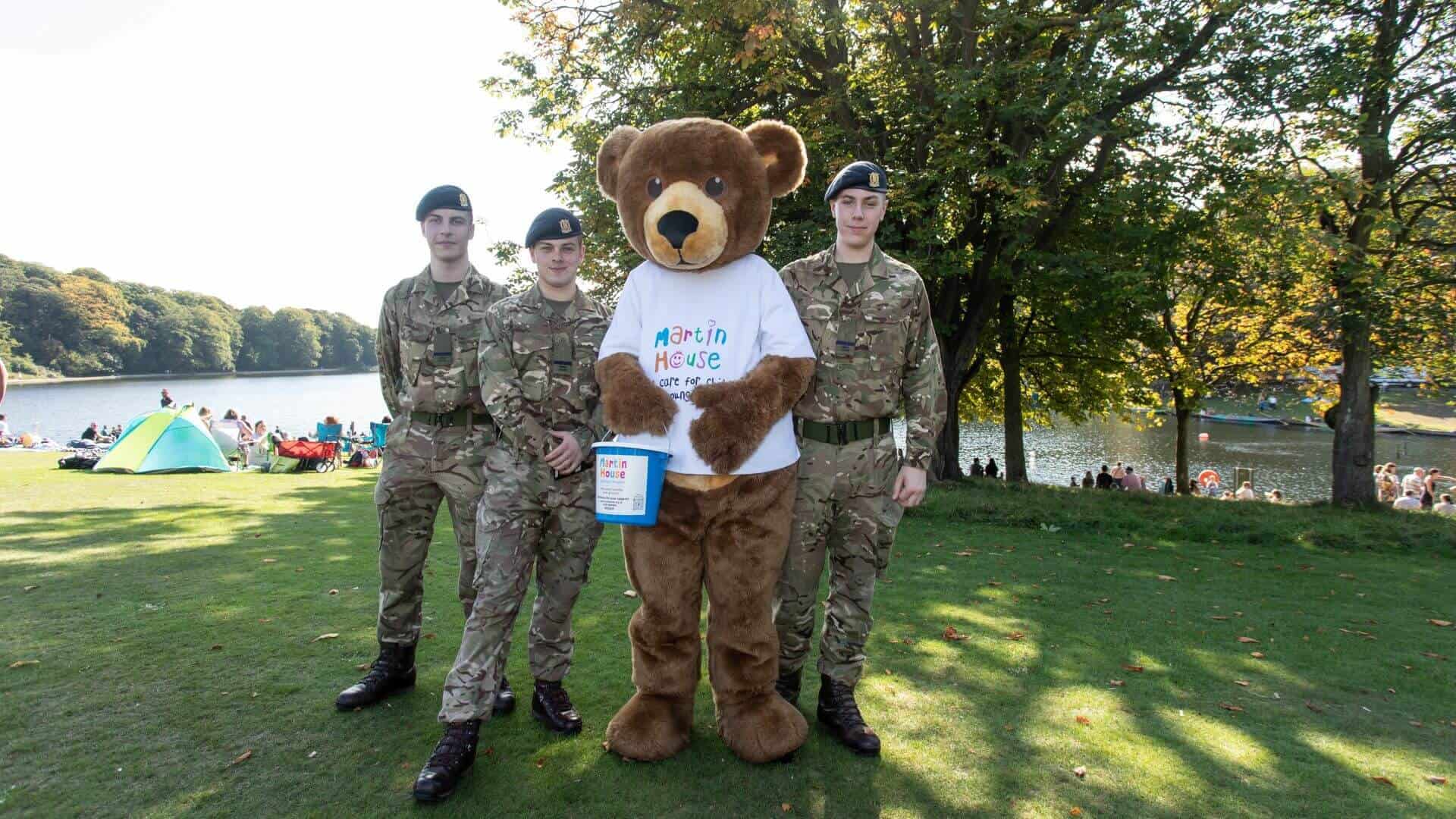 DBR army men and teddy bear Three people dressed in army uniform stood outside with teddy bear mascot.