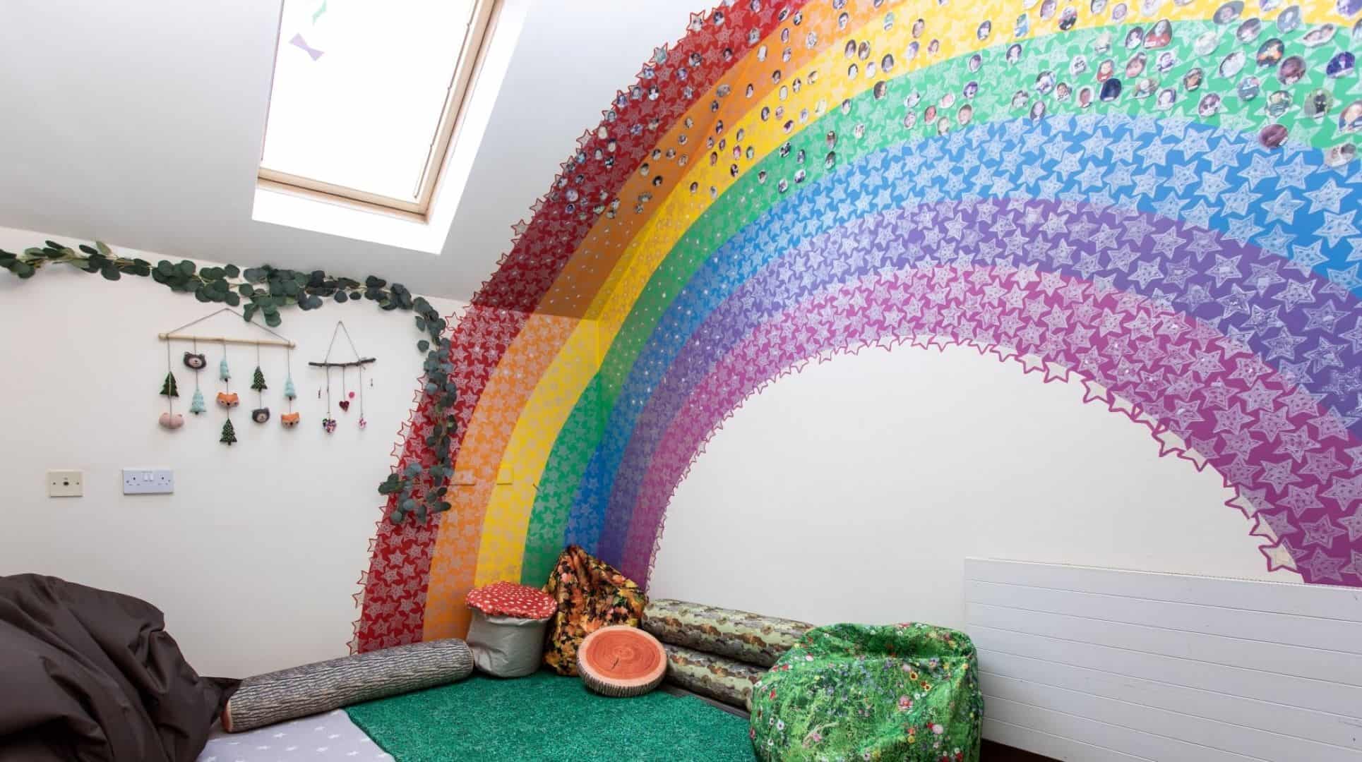 Care shot of playroom. Room with painted rainbow and stickers / decorations on wall