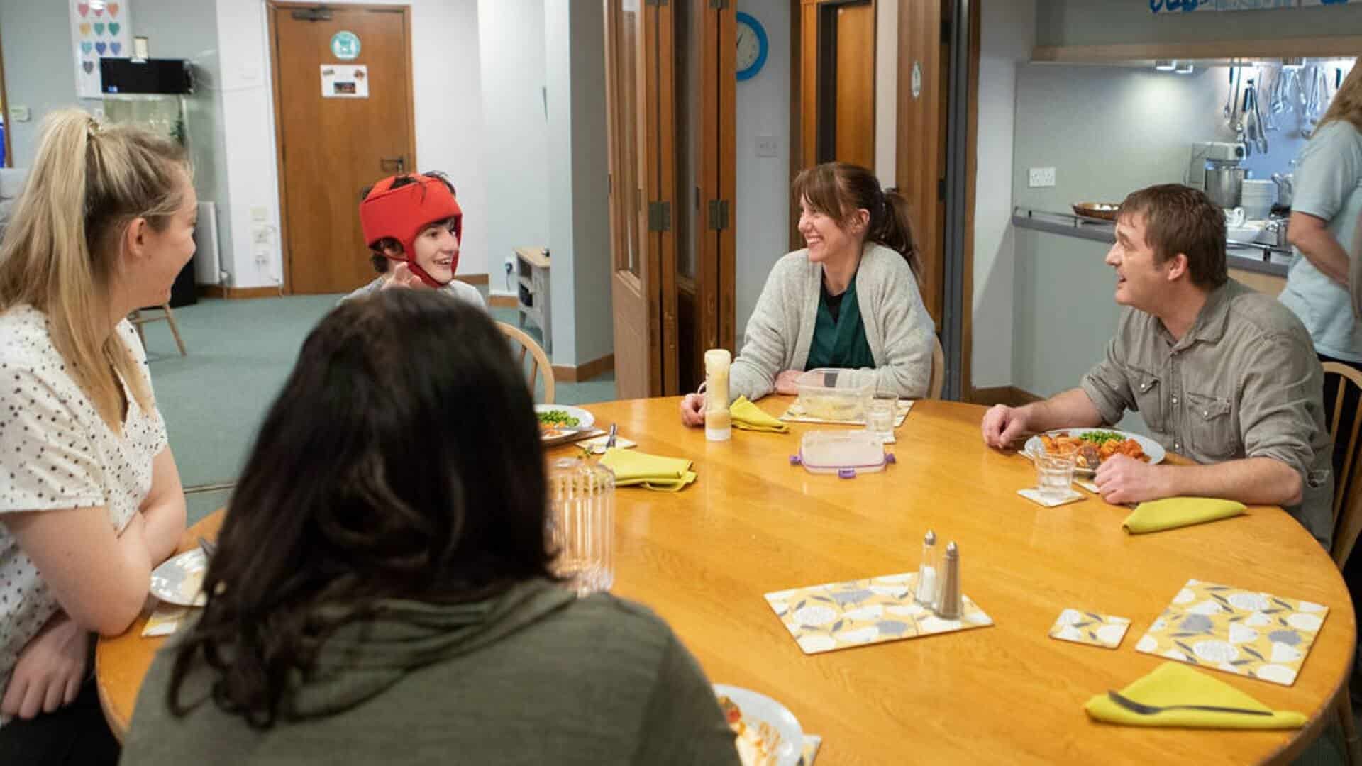 Four adults and child sat for food at a round table.