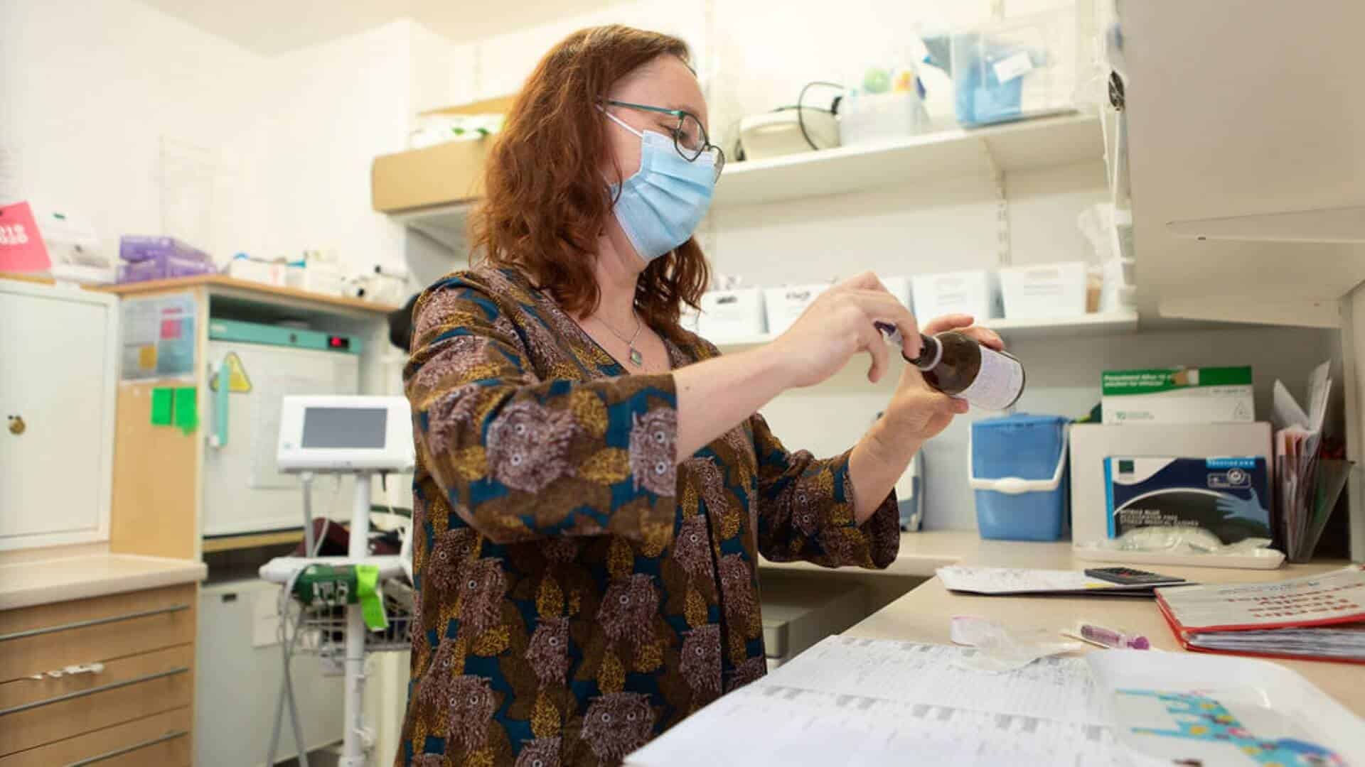 Woman in medicinal room holding a bottle of medicine.