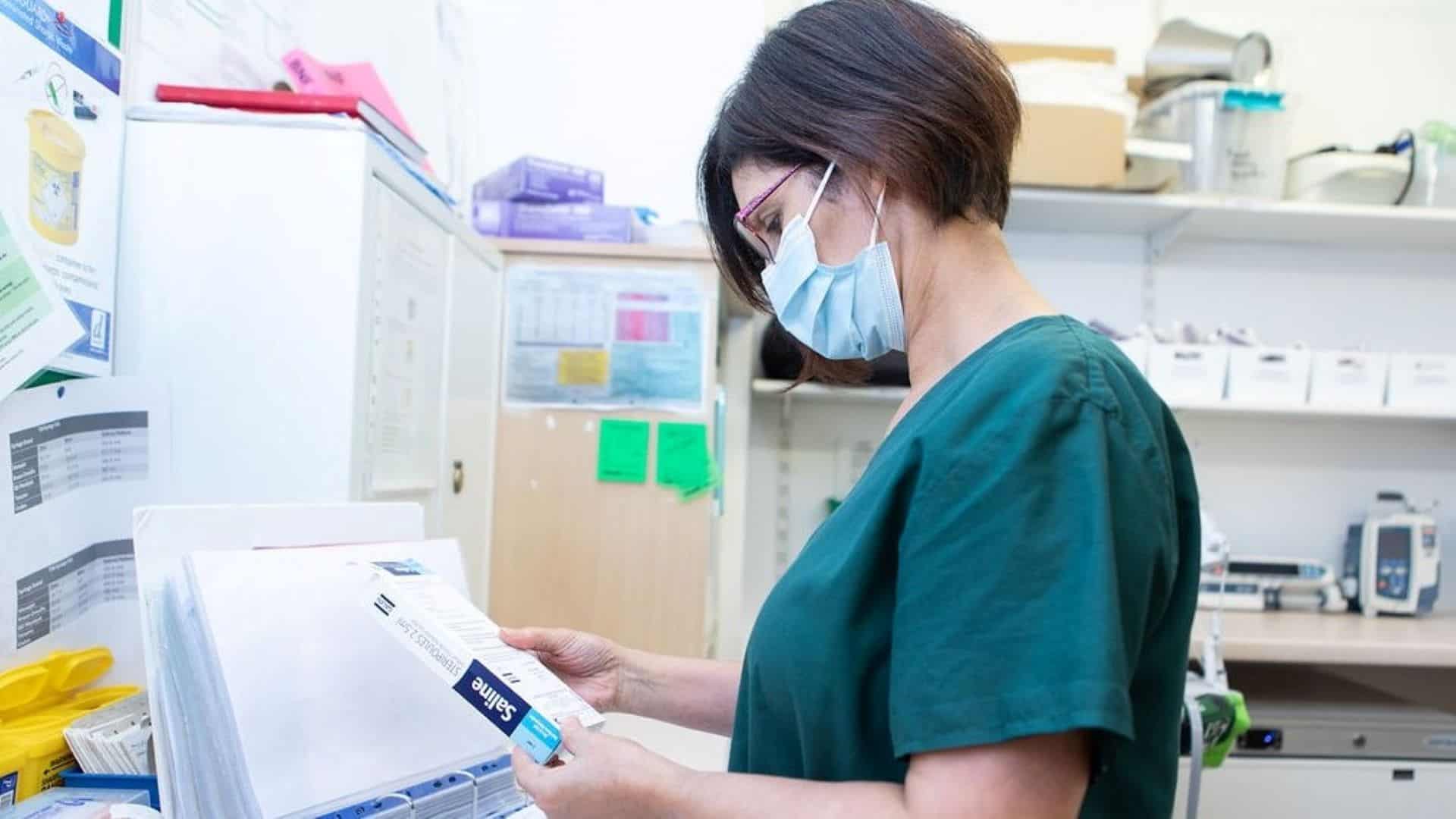 Lady wearing scrubs and masks holding perscription.