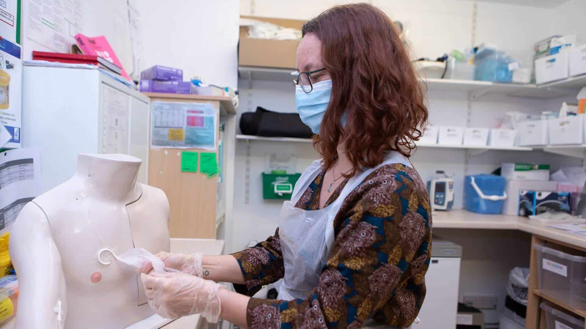 Woman showing how to put medicinal cream on a dummy.