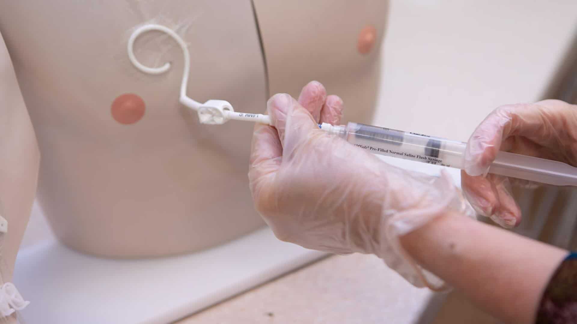 Hands showing how to put medicinal cream on a dummy.