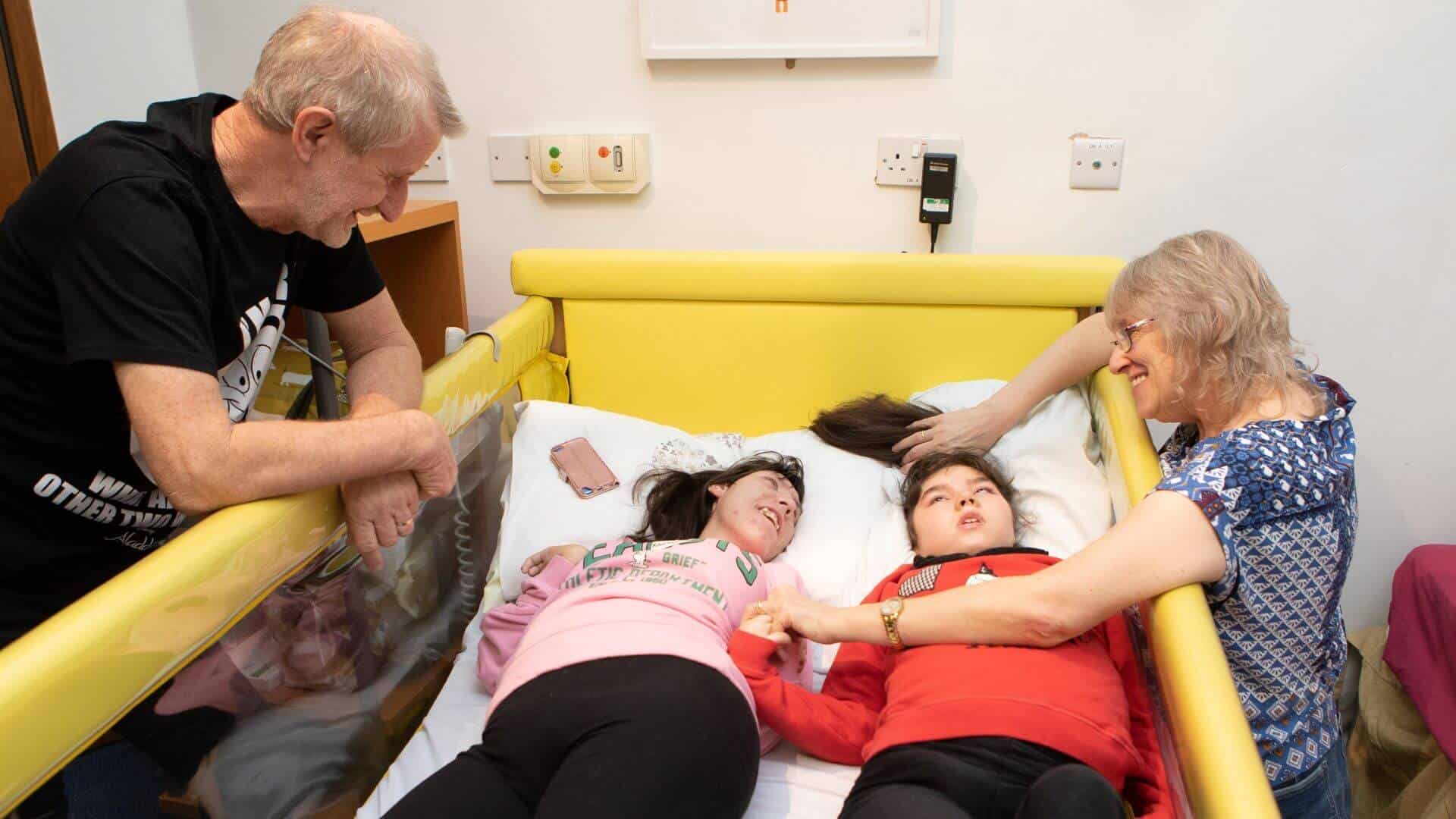 Man and woman looking over children in a bed.