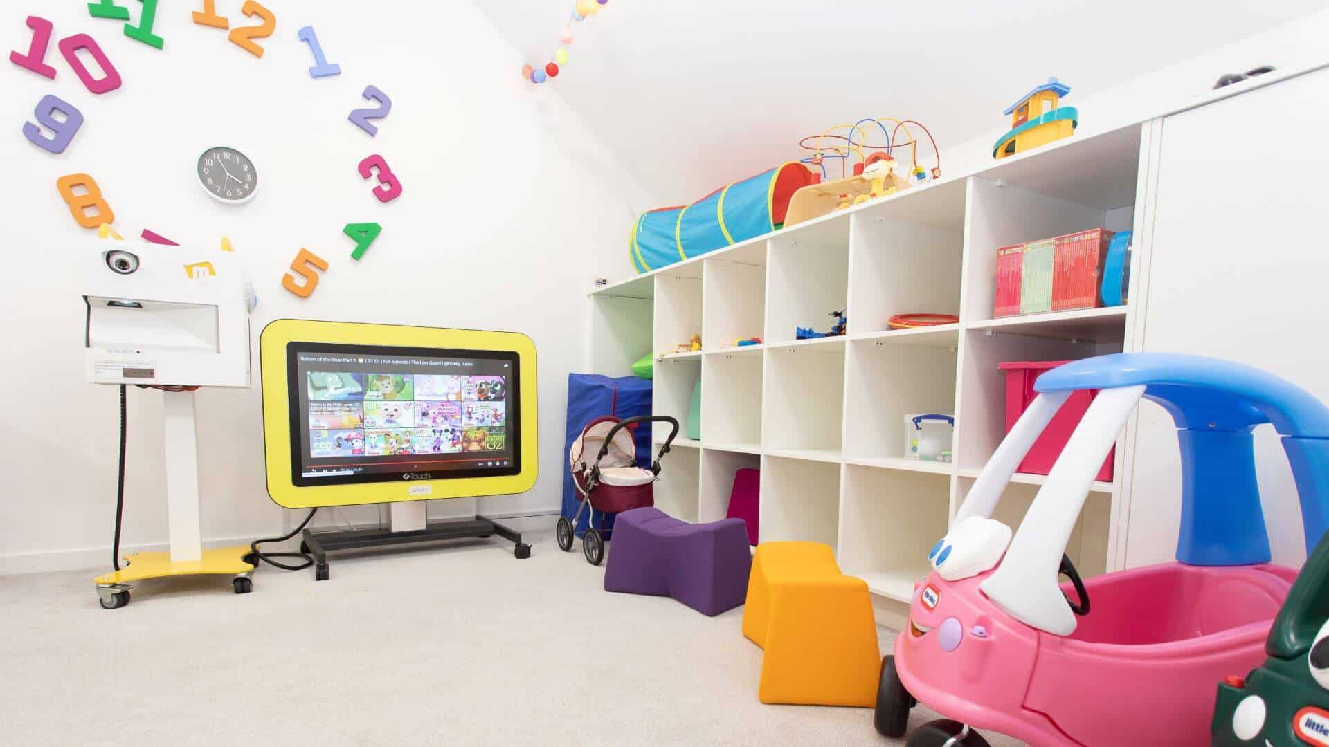 Play room with shelves and tv and toys.