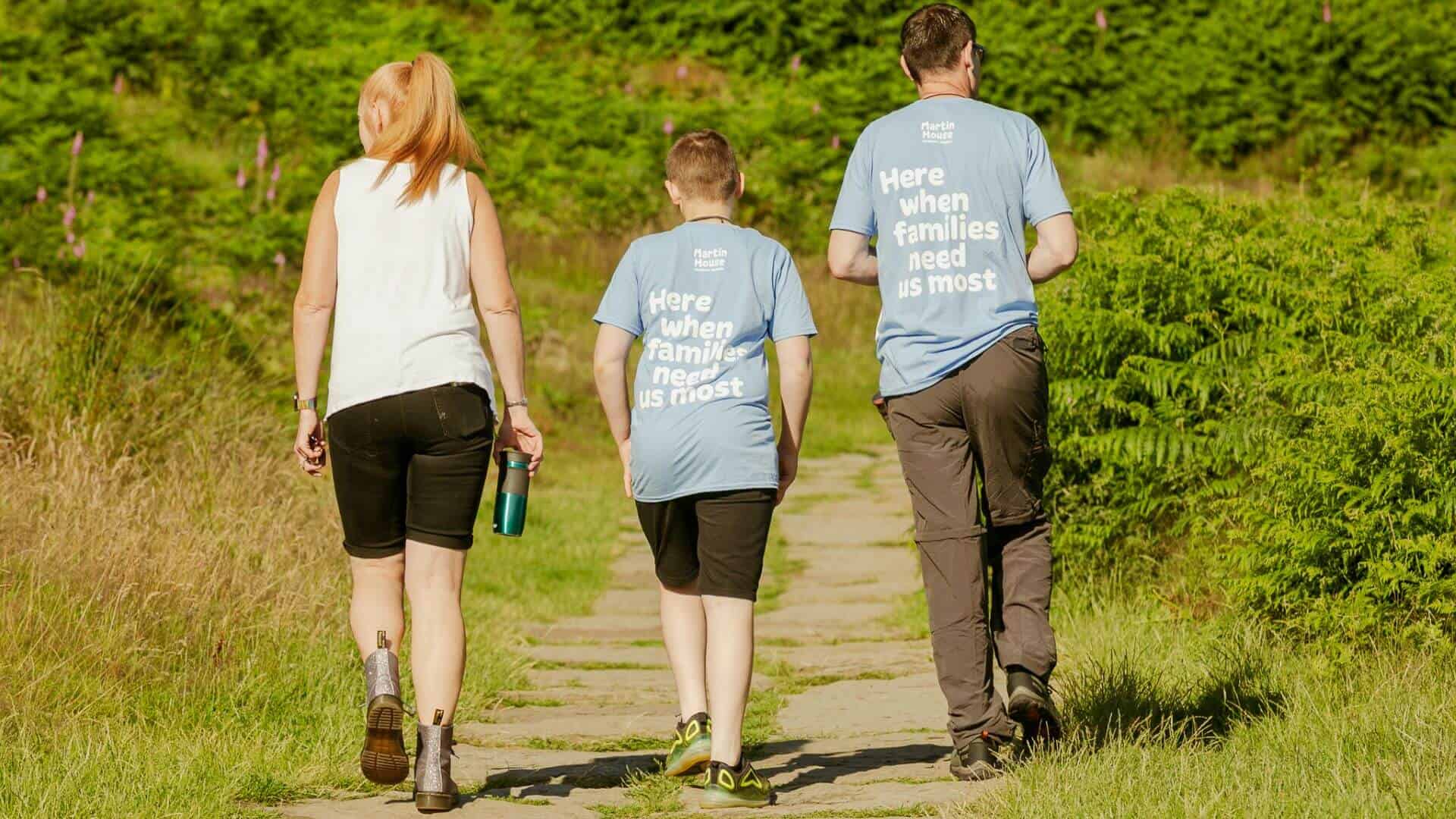 Yorkshire Three Peaks photo Back of three people walking in countryside wearing Martin House t-shirts.