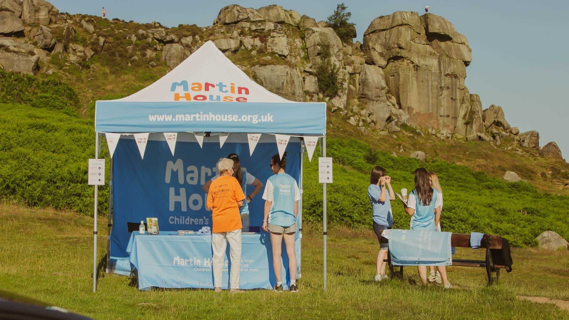 Martin House tent Martin House tent in countryside with people stood by.