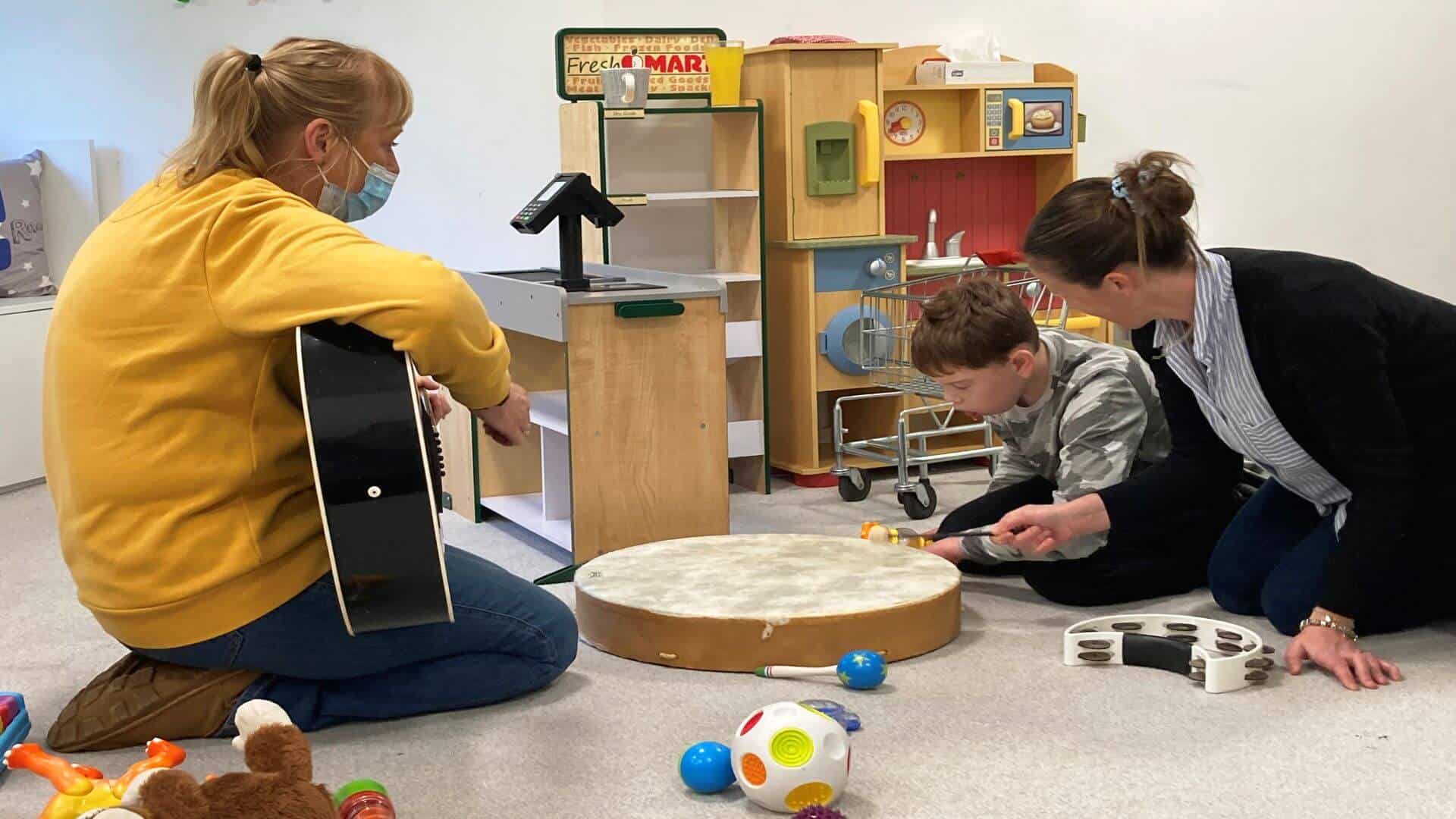 Boy with mum and music therapist in music therapy session.