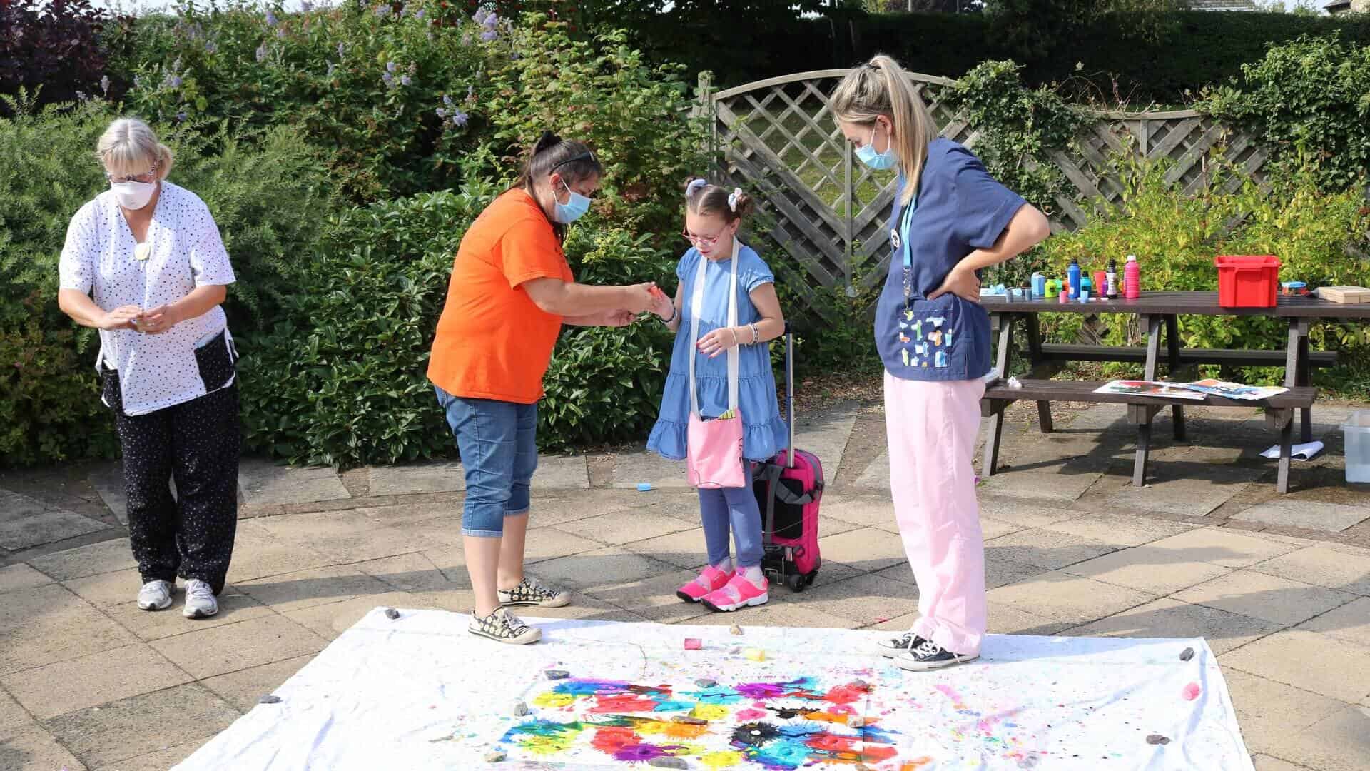 Two women and young girl doing art outside