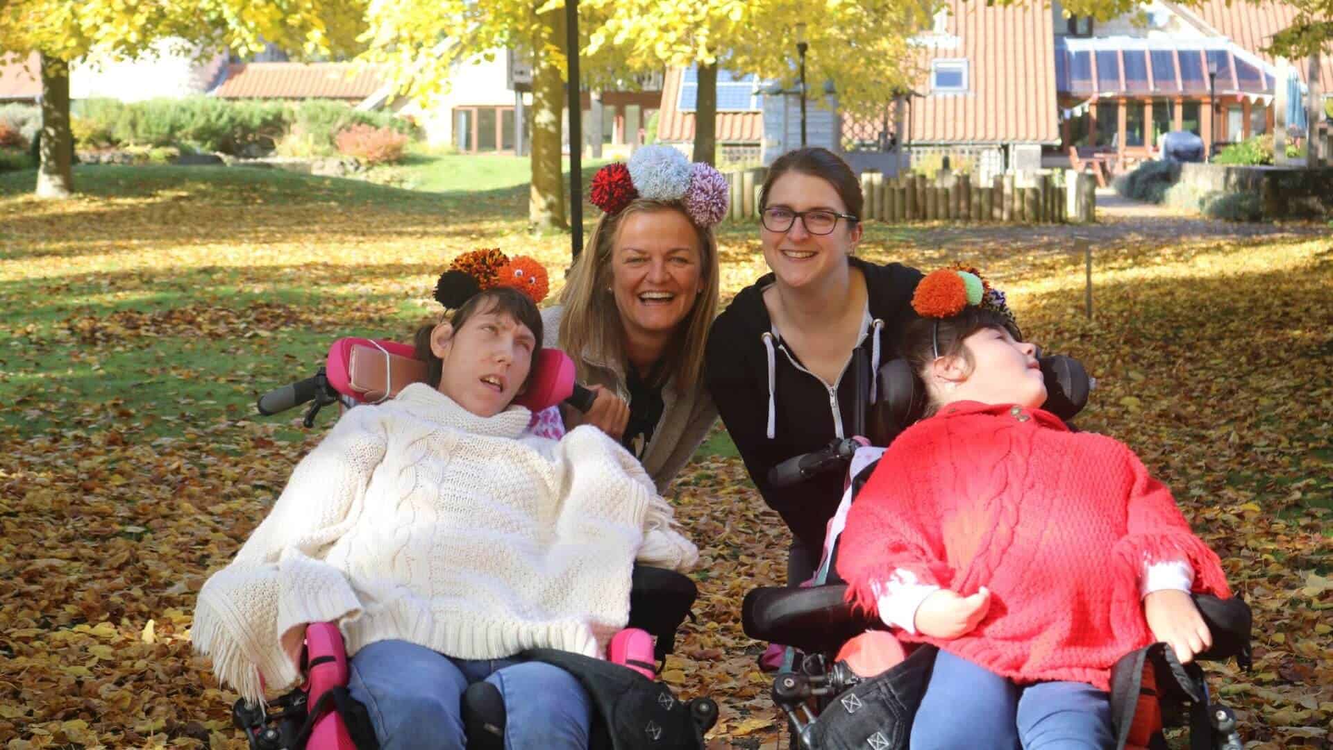 Two girls with pompom head bands with two women from care team.