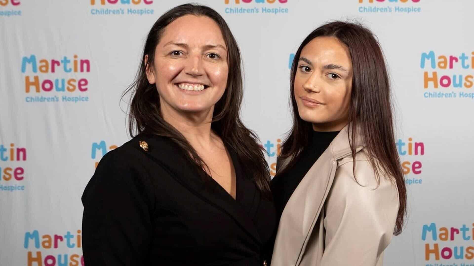 Two women in front of Martin House branded back drop.