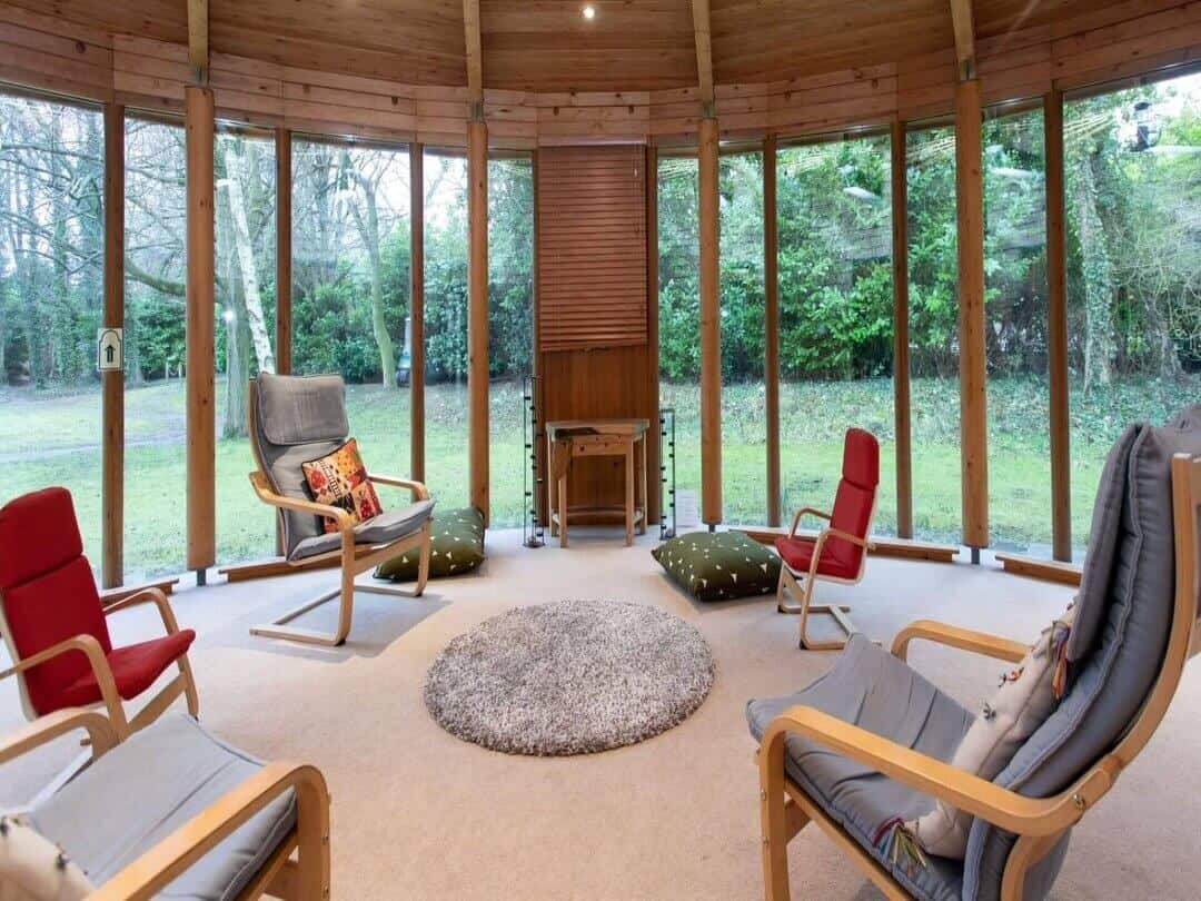 Circular room with large windows, chairs and a rug.