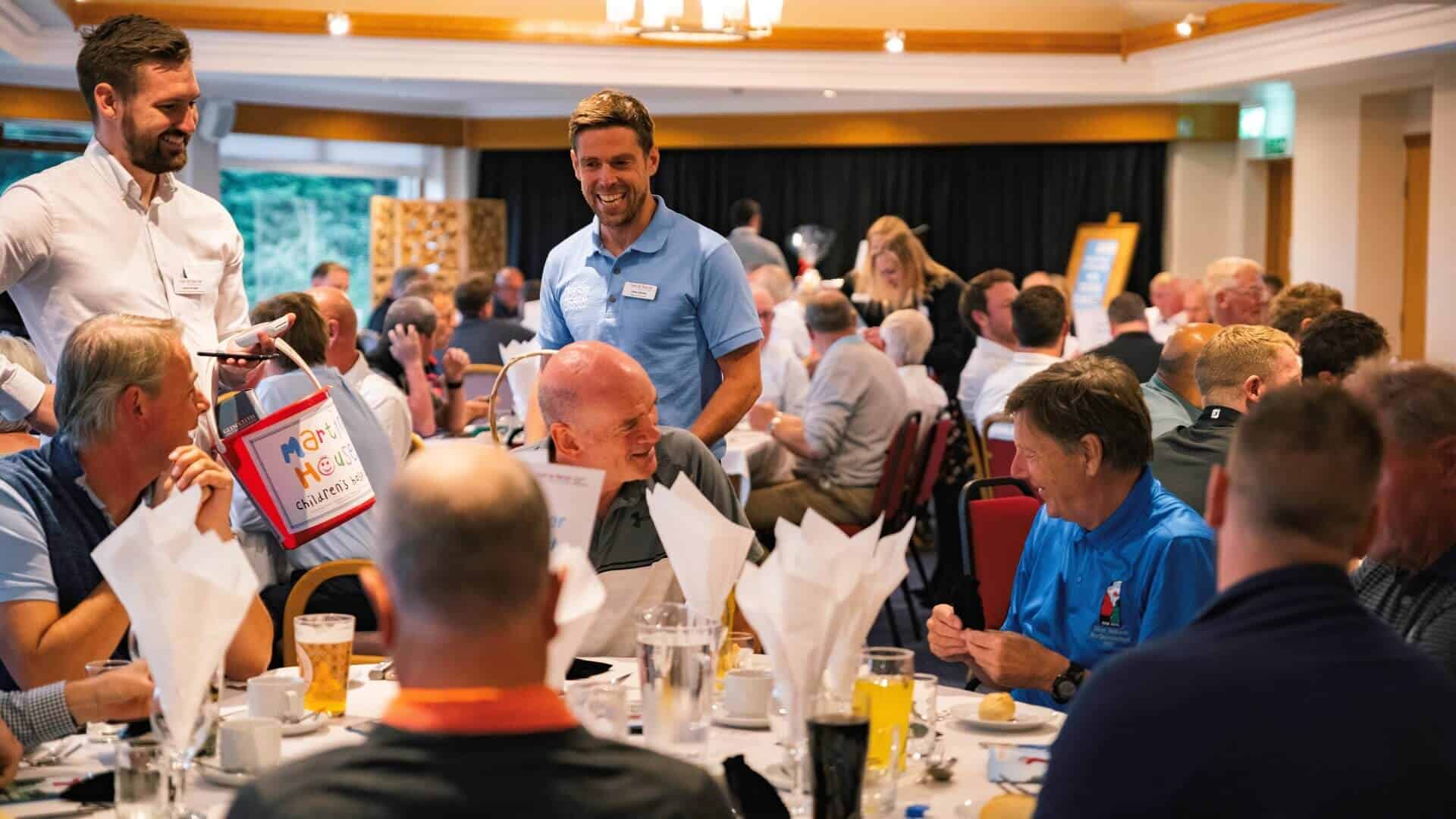 Golf Day men sat at table chatting and laughing.