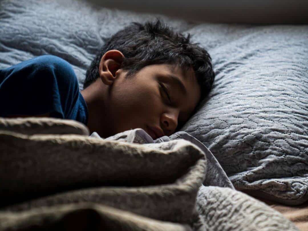 Young boy asleep in bed.