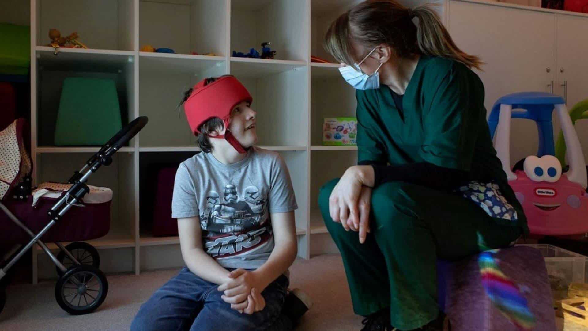 Care shoot image Young boy sat with nurse in hospice play room.