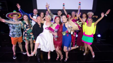 Group of couples in dance costumes celebrating with the arms in the air