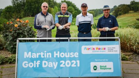 Team of four at Martin House Golf Day event with sign saying Martin House Golf Day 2021.