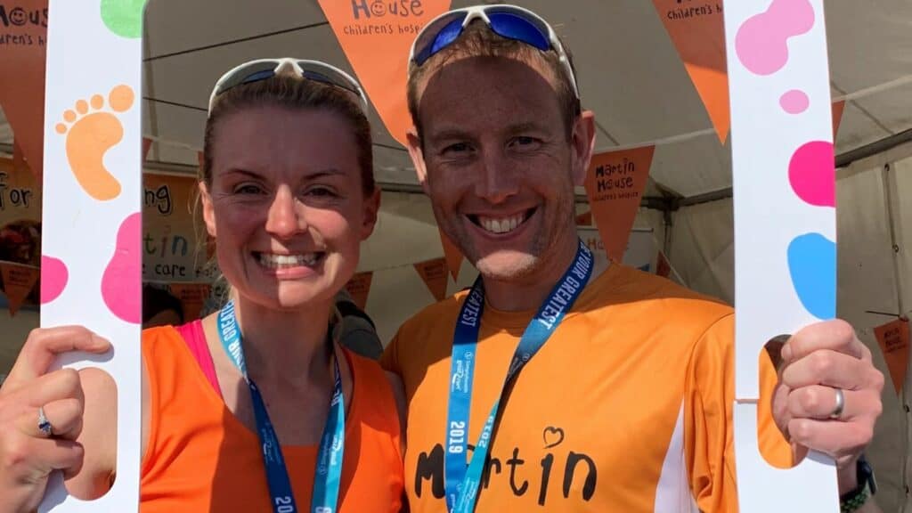 Man and woman holding cardboard frame for a picture after running for Martin House.