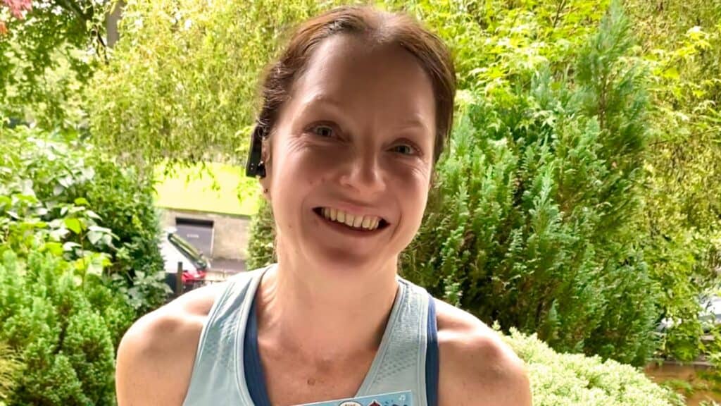 Jenny wearing running vest in garden with trees in background.