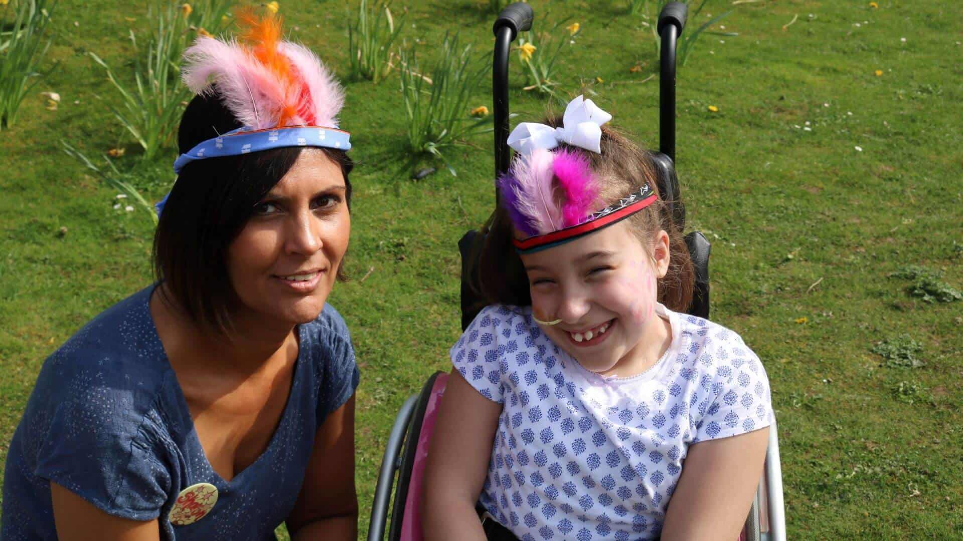 Woman and young girl smiling wearing feather headbands