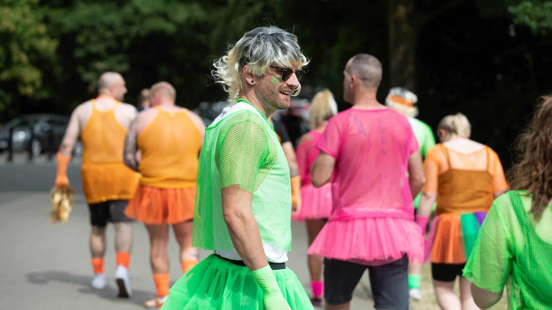 Man wearing funny neon fancy dress with wig and tutu