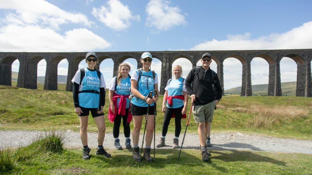 Yorkshire Three Peaks walkers smiling under viaduct.