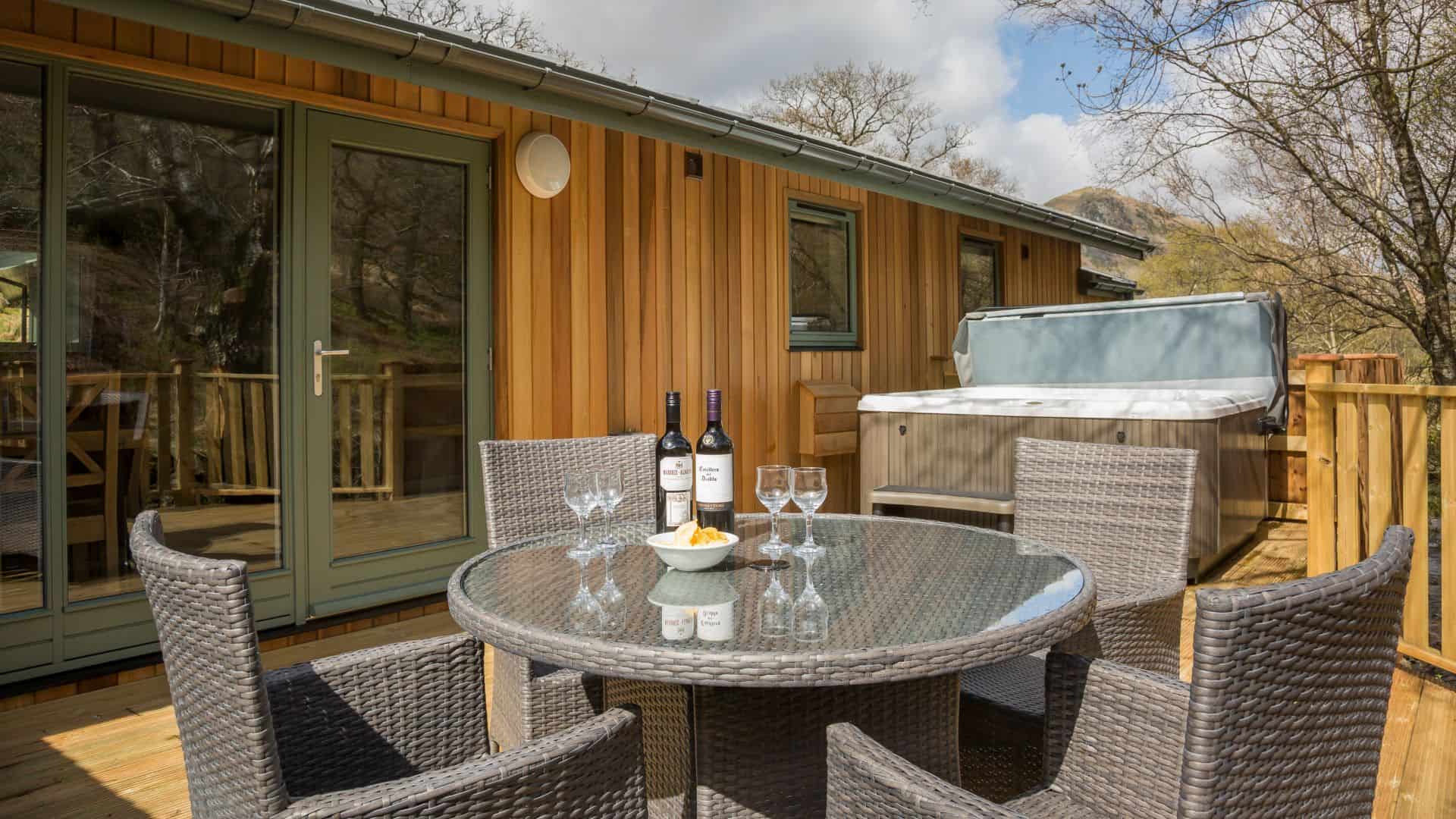 Outdoor seating area with hot tub outside lodge.