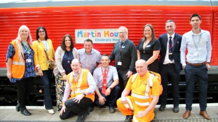 The charter train charity fundraising team gather in front of the locomotive with the Martin House Children's Hospice logo.